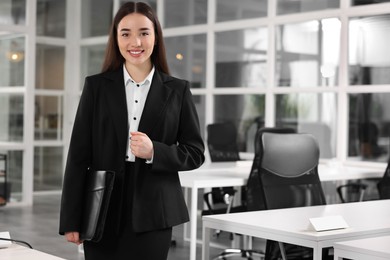 Photo of Happy real estate agent with leather portfolio indoors. Space for text