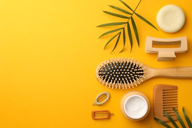 Photo of Flat lay composition with wooden brushes and different hair products on orange background. Space for text