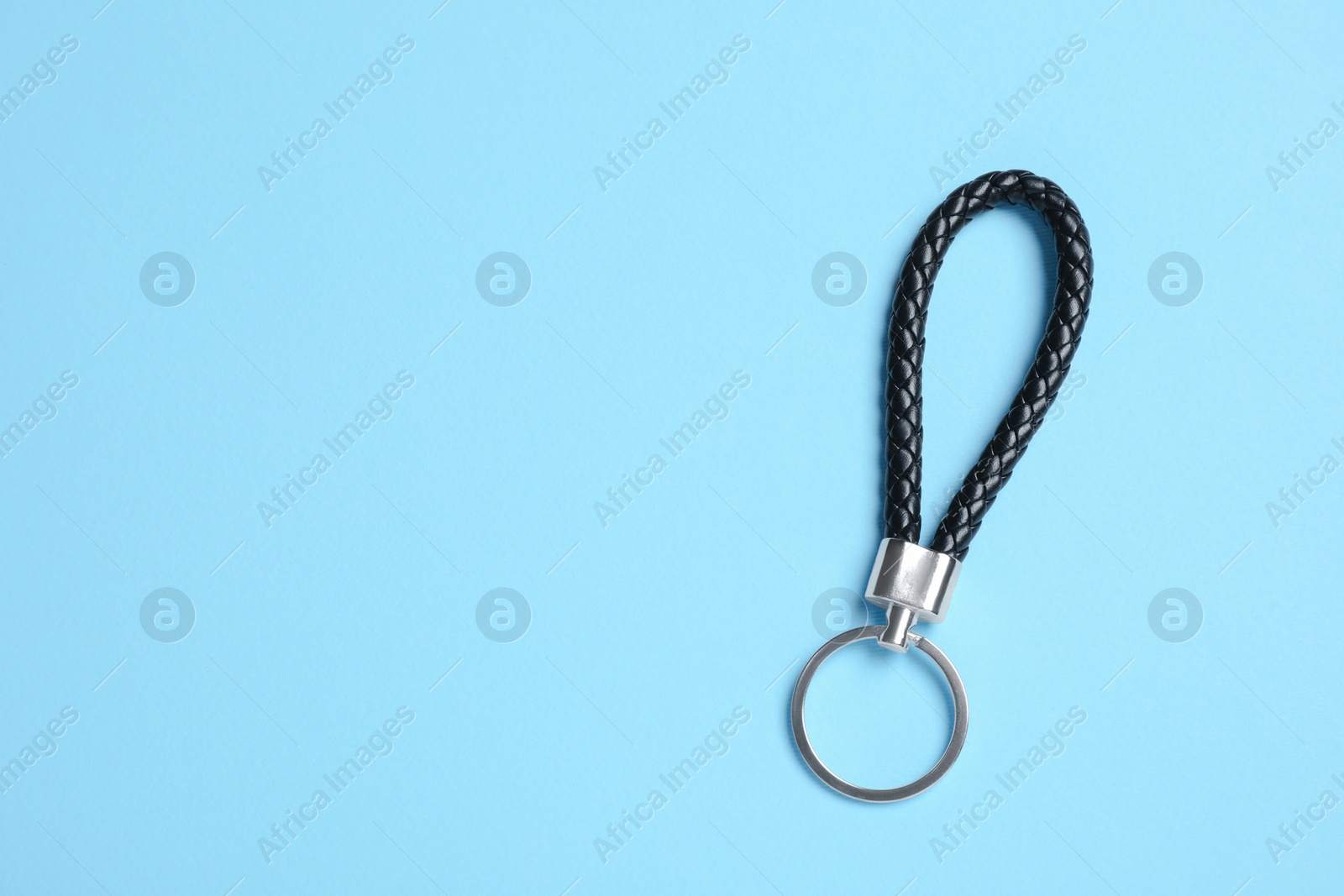 Photo of Black leather keychain on light blue background, top view. Space for text