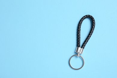 Photo of Black leather keychain on light blue background, top view. Space for text