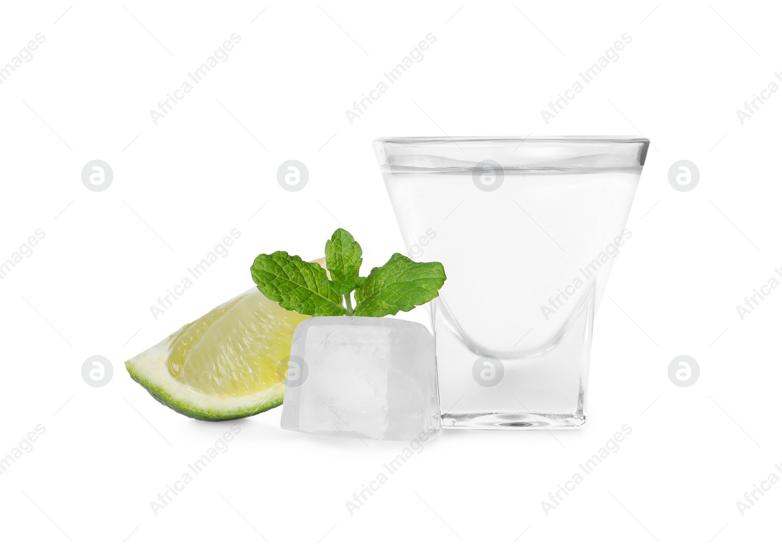 Photo of Shot glass of vodka, lime slice and ice cube isolated on white