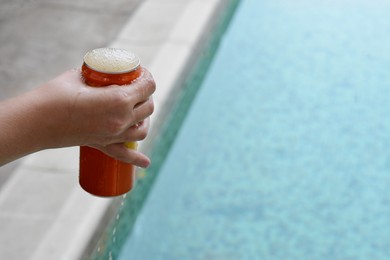 Photo of Woman holding tasty open canned beverage near swimming pool, closeup. Space for text