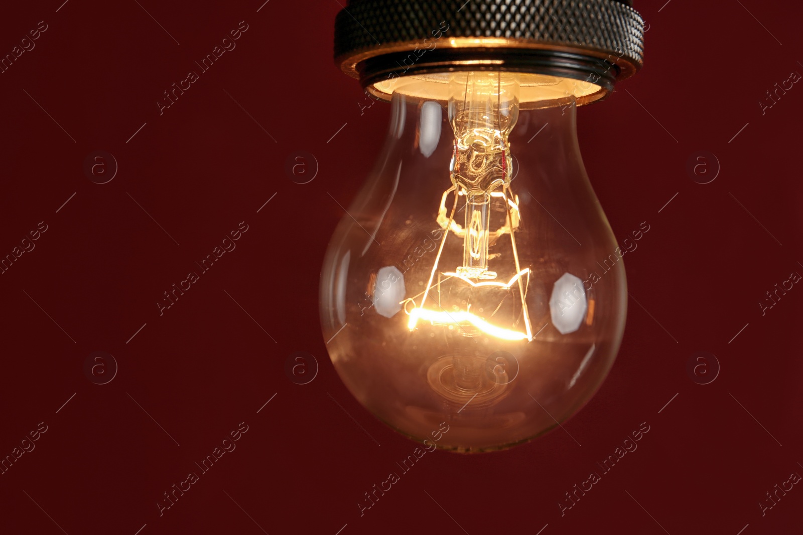 Photo of Pendant lamp with light bulb against dark red background, space for text