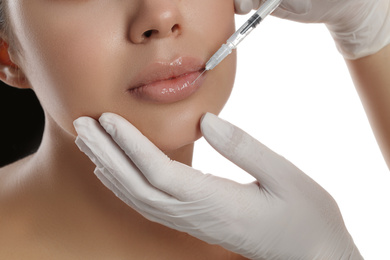 Photo of Young woman getting lips injection on white background, closeup