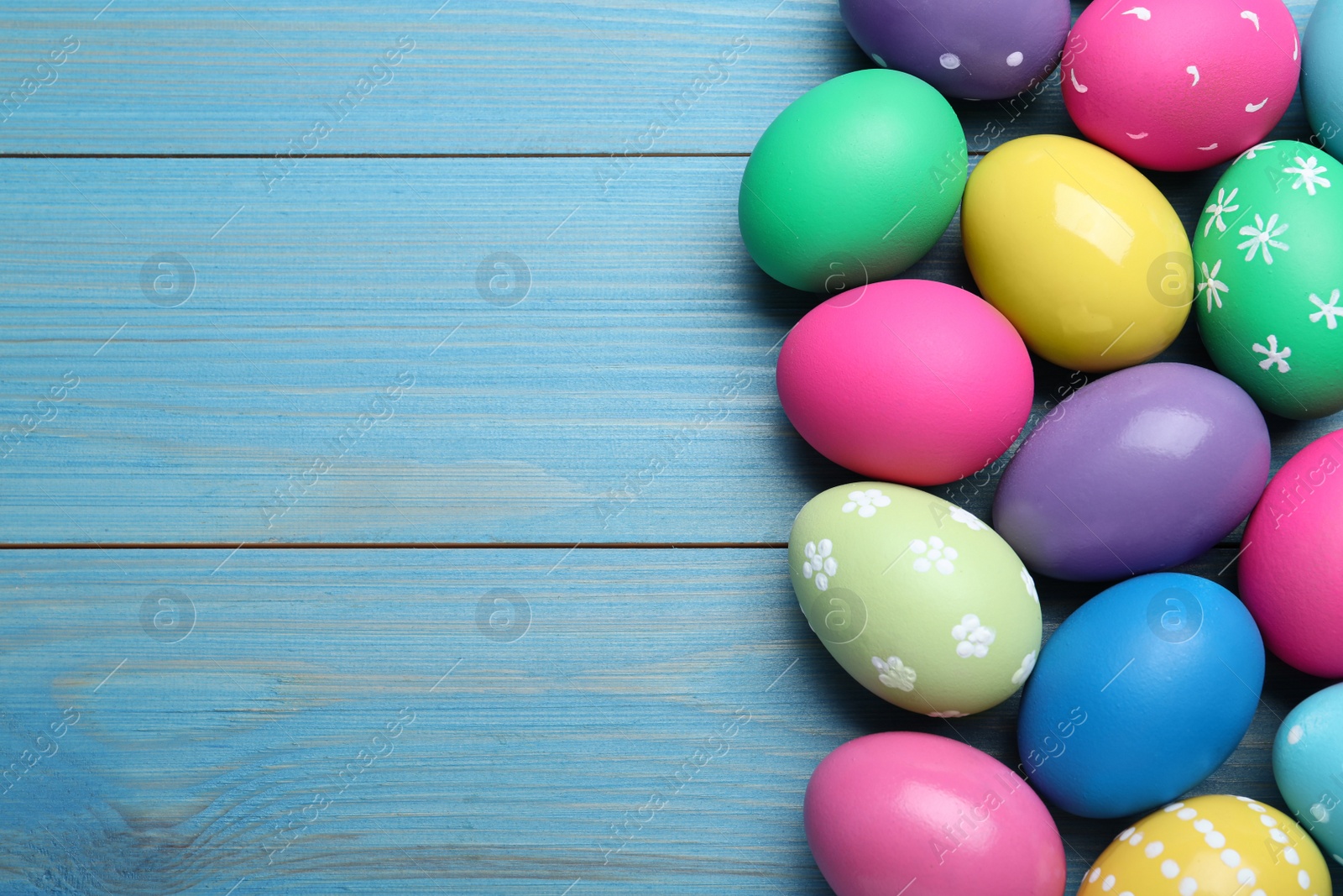 Photo of Colorful eggs on blue wooden background, flat lay with space for text. Happy Easter