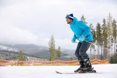 Male skier on slope at resort, space for text. Winter vacation