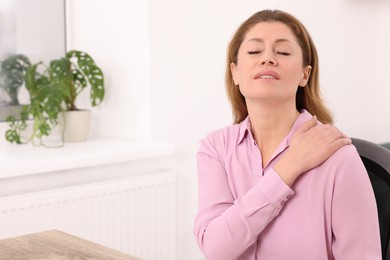 Woman suffering from pain in shoulder indoors, space for text. Arthritis symptoms