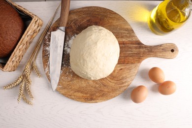 Photo of Fresh dough sprinkled with flour and other ingredients on white wooden table, flat lay