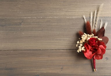 Beautiful boutonniere on wooden background, top view. Space for text