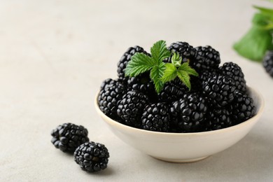 Photo of Bowl of fresh blackberries with leaves on white table