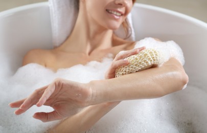 Photo of Woman rubbing her arm with sponge while taking bath, closeup