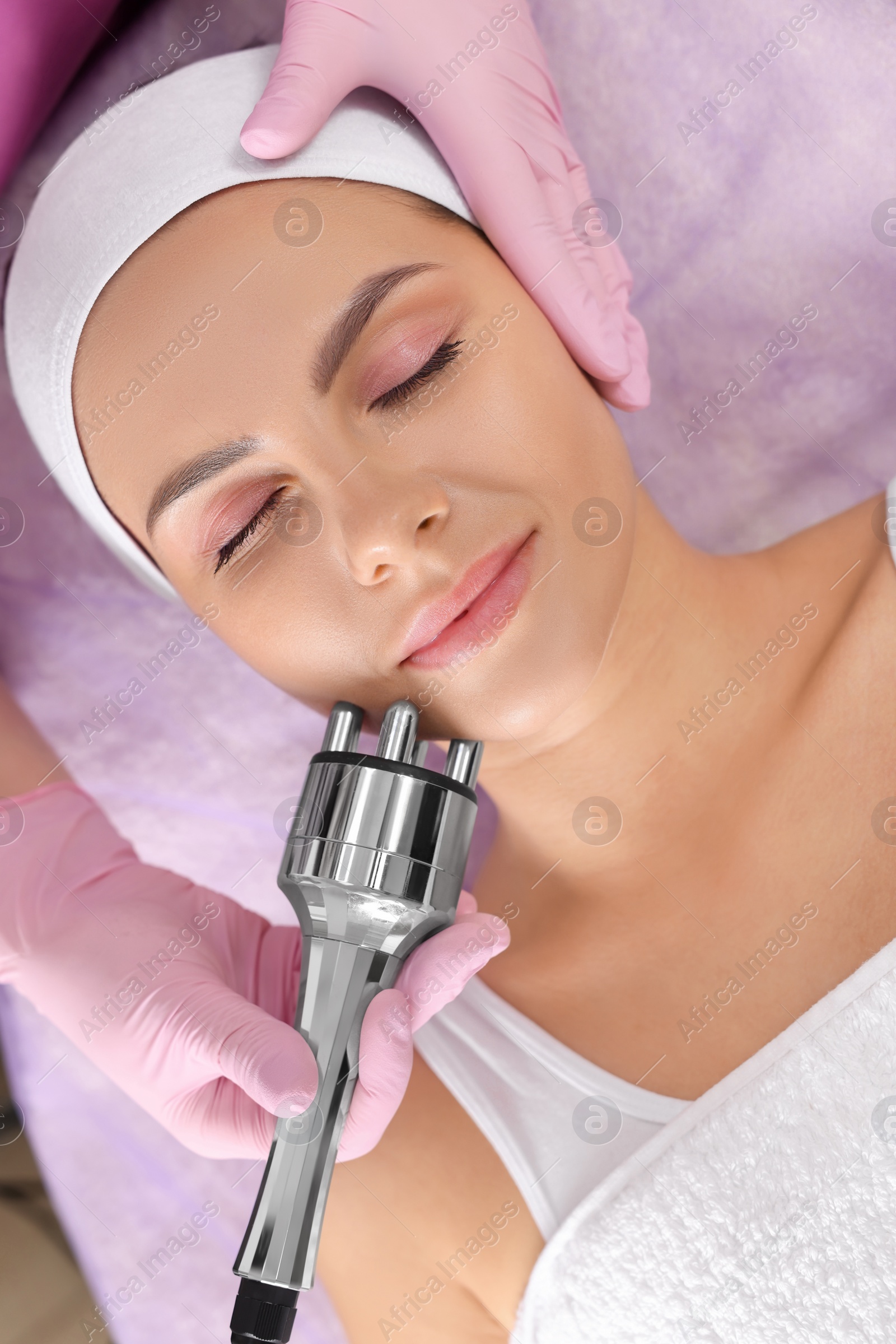 Photo of Young woman undergoing cosmetic procedure in beauty salon, top view. Microcurrent therapy