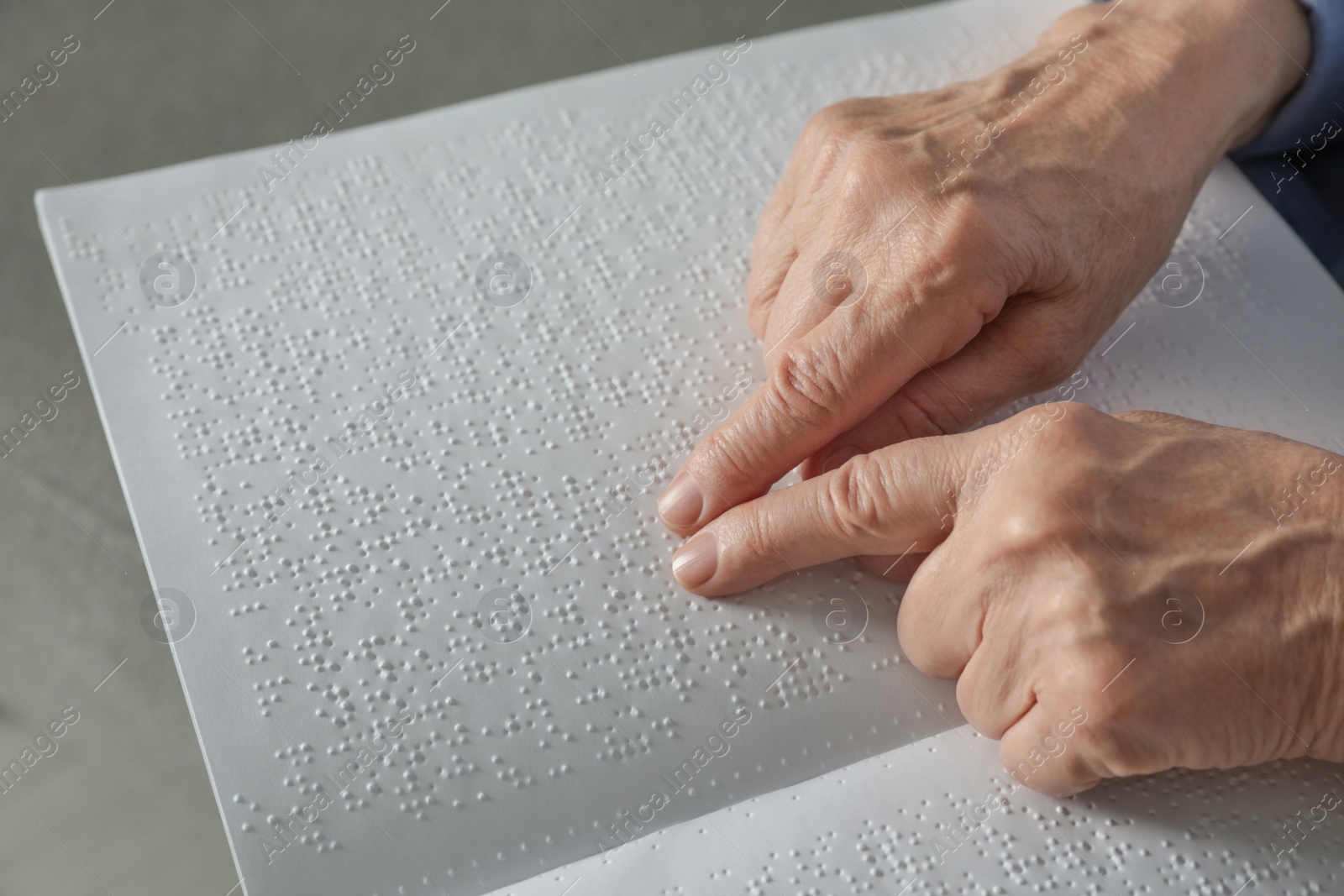 Photo of Blind senior person reading book written in Braille, closeup