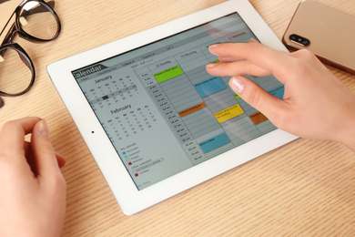 Photo of Woman using calendar app on tablet in office, closeup