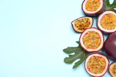 Fresh ripe passion fruits (maracuyas) with green leaves on light background, flat lay. Space for text