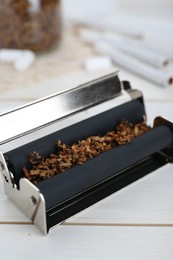 Roller with tobacco on white wooden table, closeup. Making hand rolled cigarettes