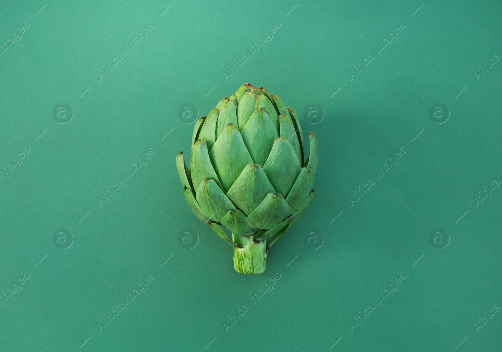 Photo of Whole fresh raw artichoke on green background, top view. Space for text