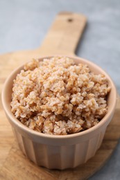 Photo of Tasty wheat porridge in bowl on grey table, closeup