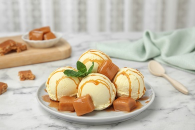 Delicious ice cream with caramel and sauce served on table