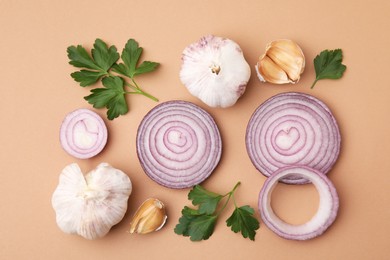 Photo of Fresh red onions, garlic and parsley on beige background, flat lay