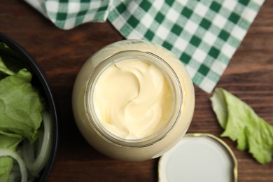 Photo of Jar of delicious mayonnaise and fresh salad on wooden table, flat lay