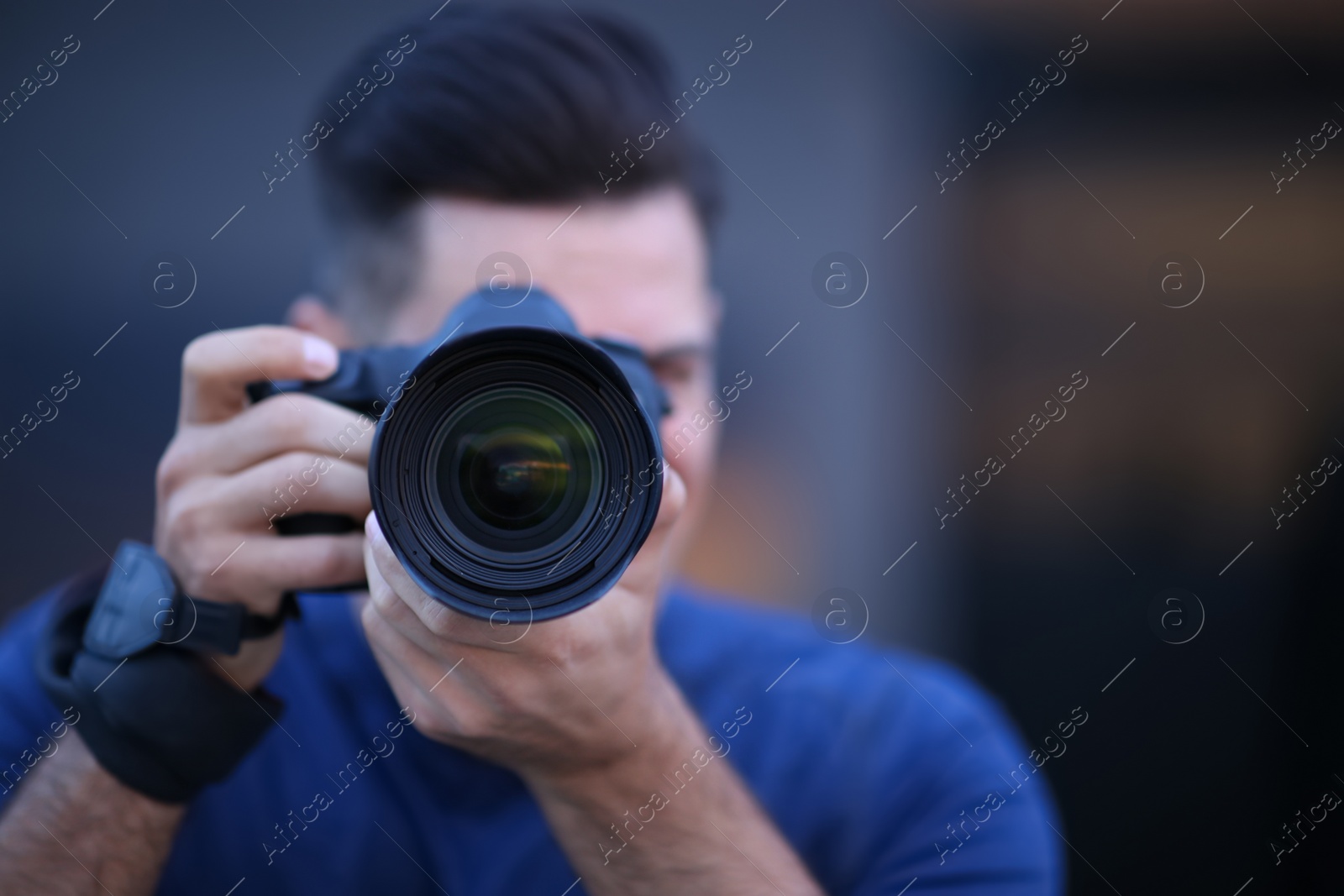 Photo of Photographer taking picture with professional camera outdoors in evening, focus on lens