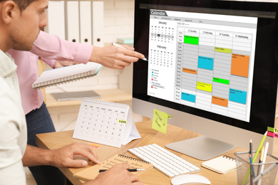 Colleagues working with calendar app on computer in office, closeup