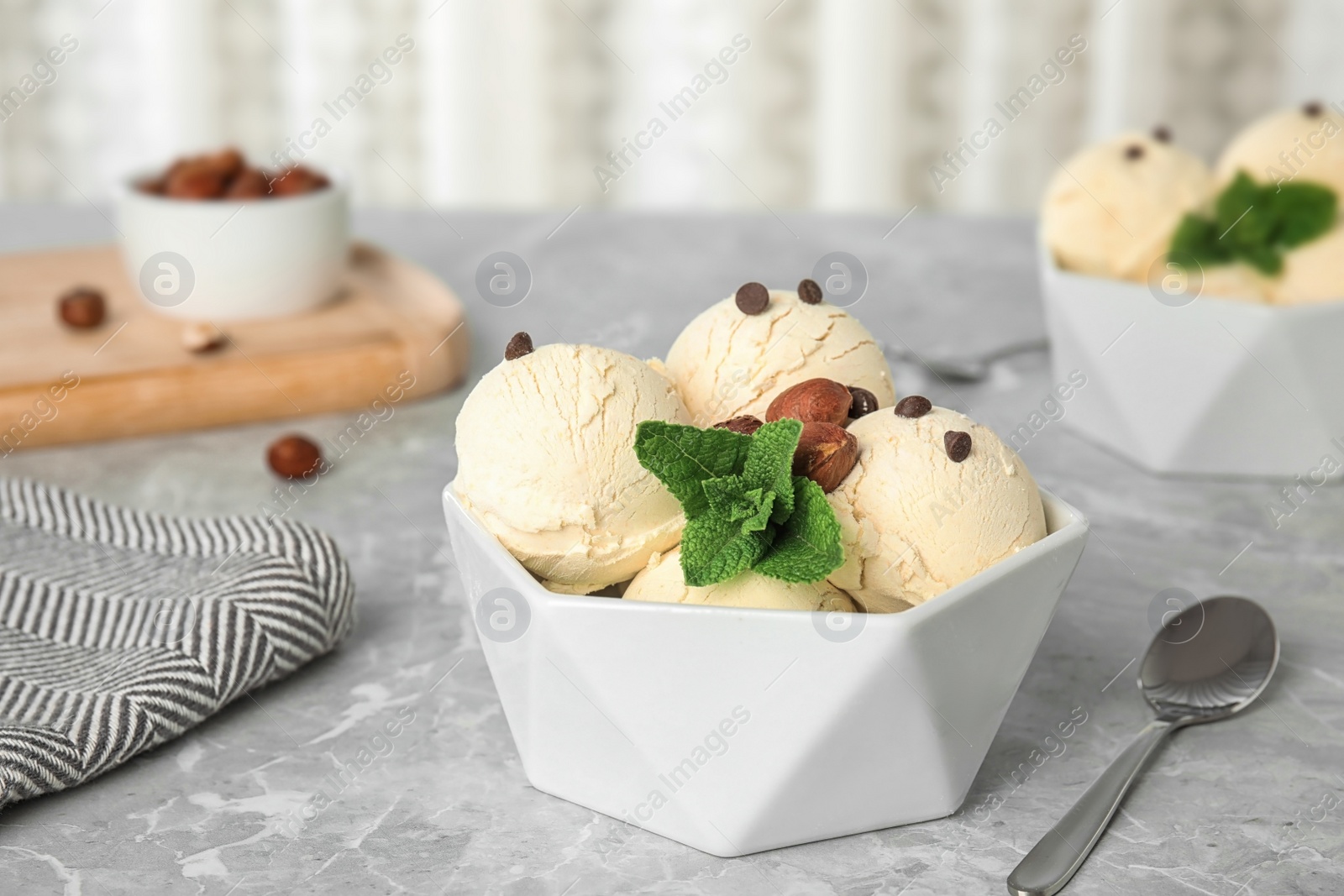 Photo of Delicious vanilla ice cream with mint, hazelnuts and chocolate chips served on table