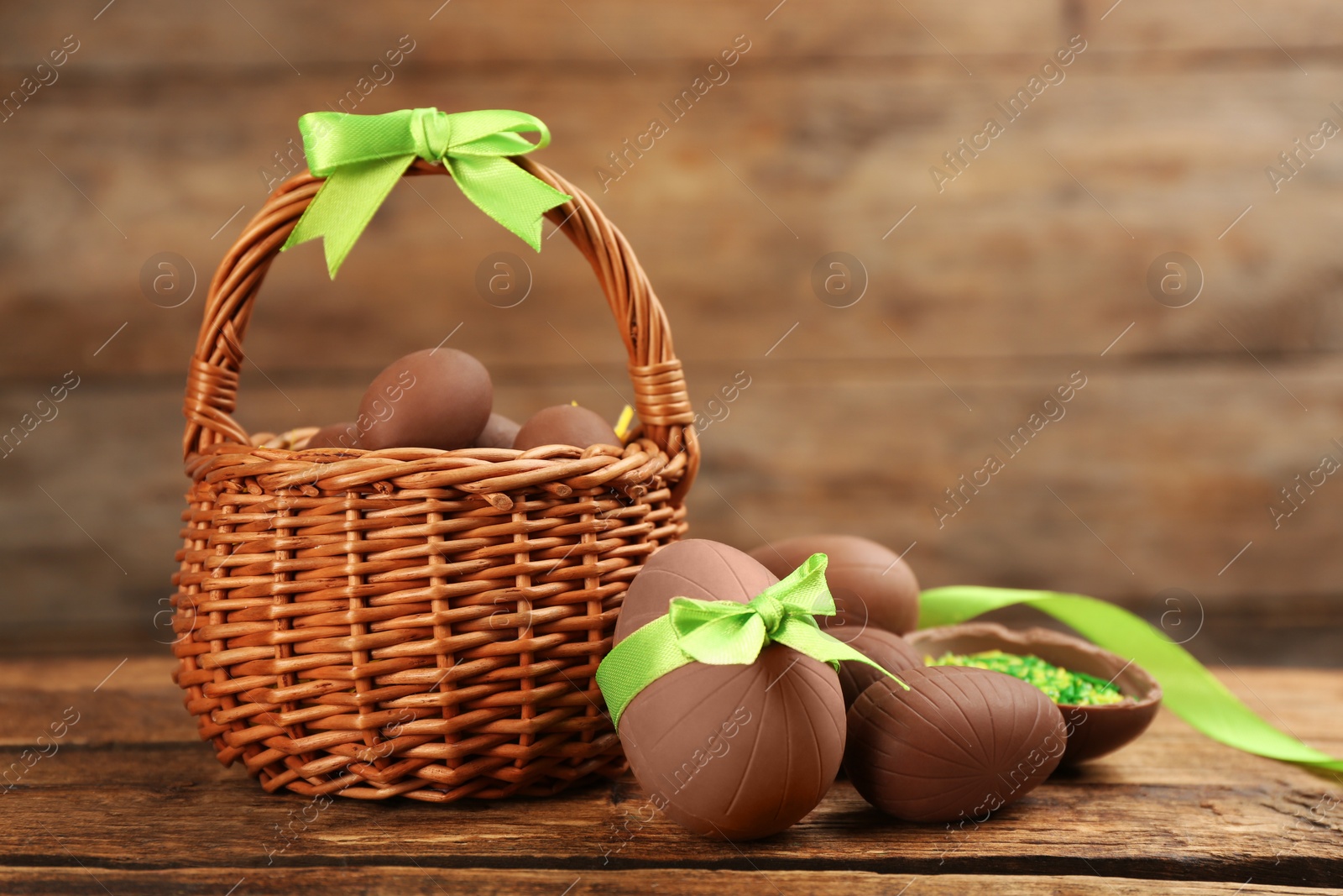 Photo of Sweet chocolate eggs and wicker basket on wooden table