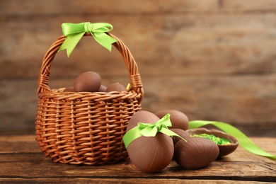 Sweet chocolate eggs and wicker basket on wooden table