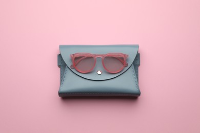 Photo of Stylish woman's bag and sunglasses on pink background, top view