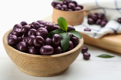 Tasty acai berries in bowl on white table, closeup