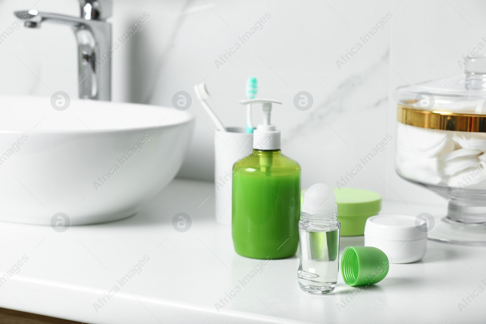 Photo of Roll-on deodorant and toiletry on countertop in bathroom, space for text