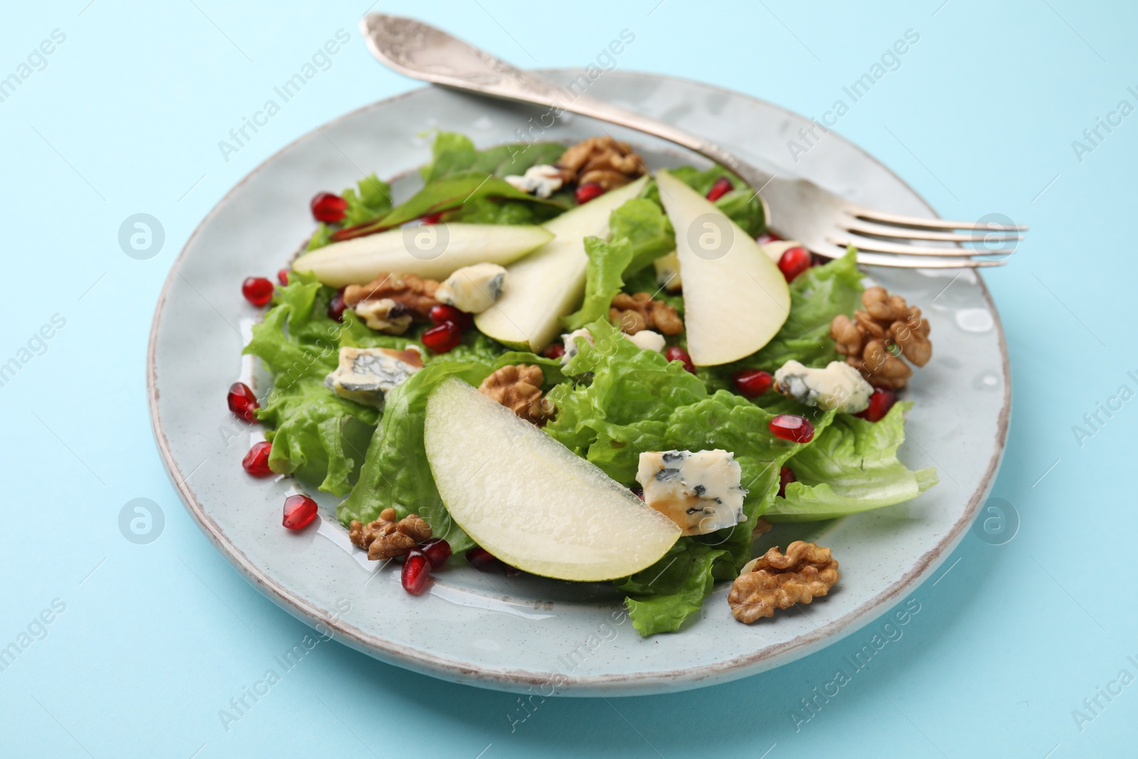 Photo of Delicious pear salad on light blue background, closeup