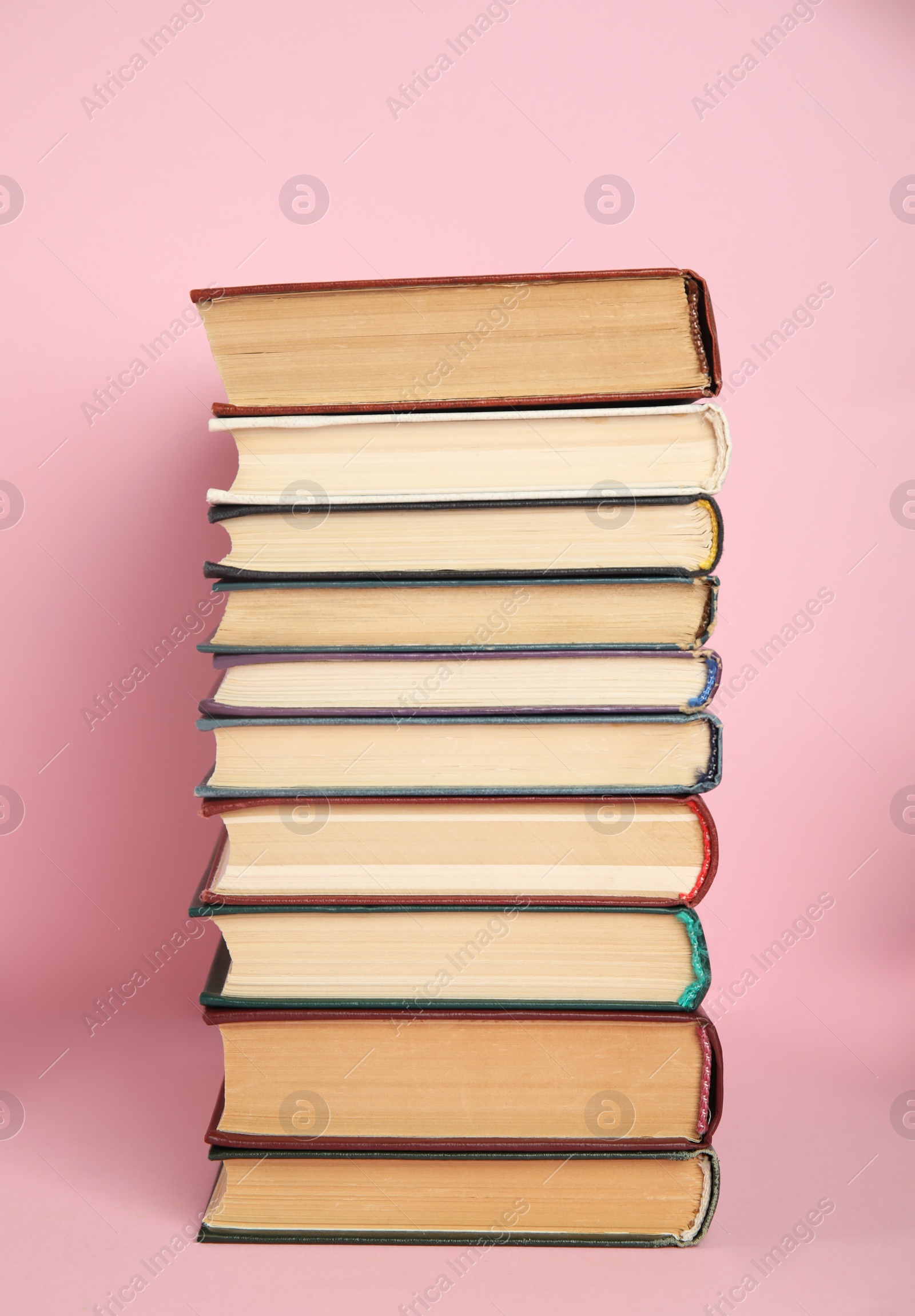 Photo of Stack of different hardcover books on pink background