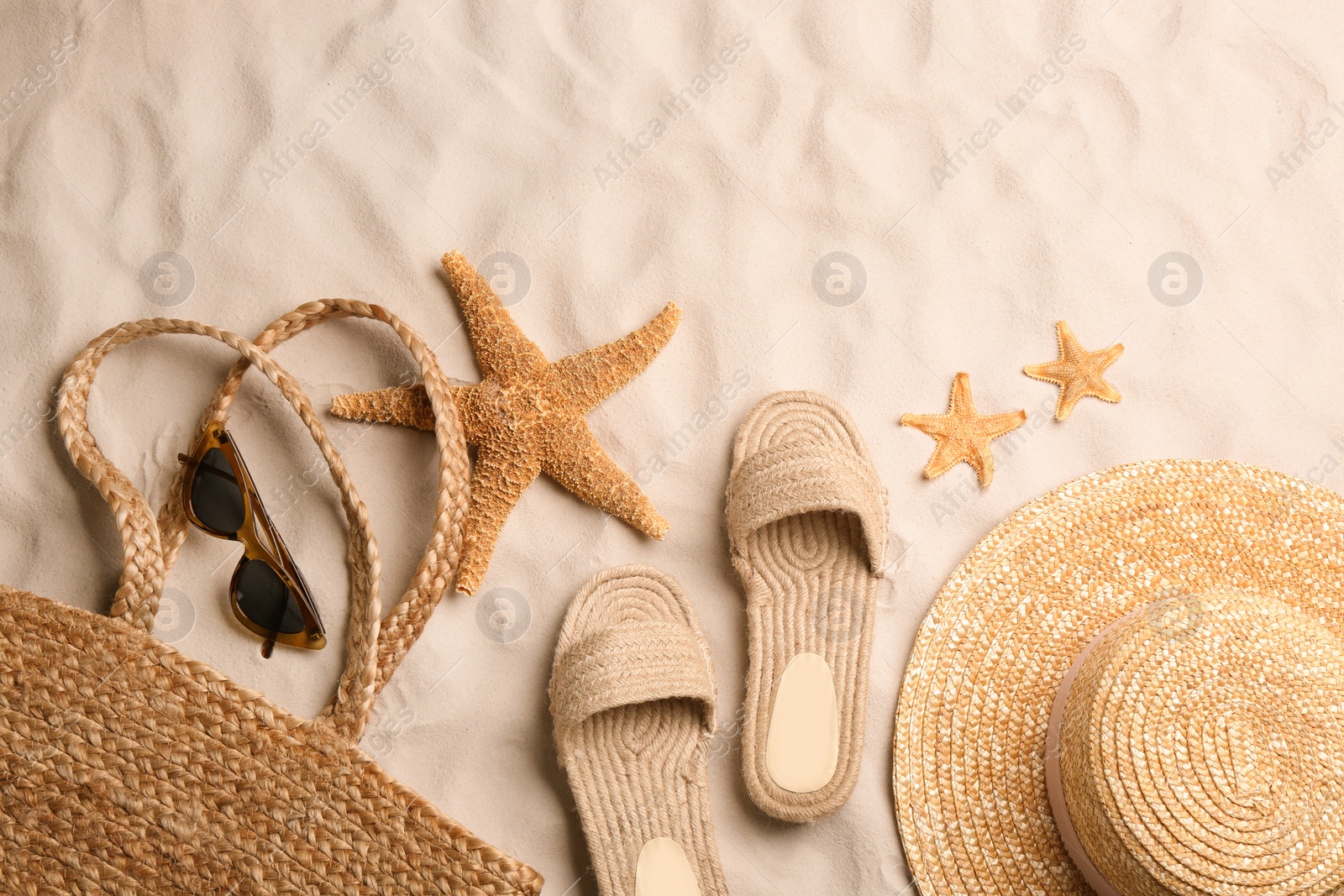 Photo of Different beach accessories on sand, flat lay