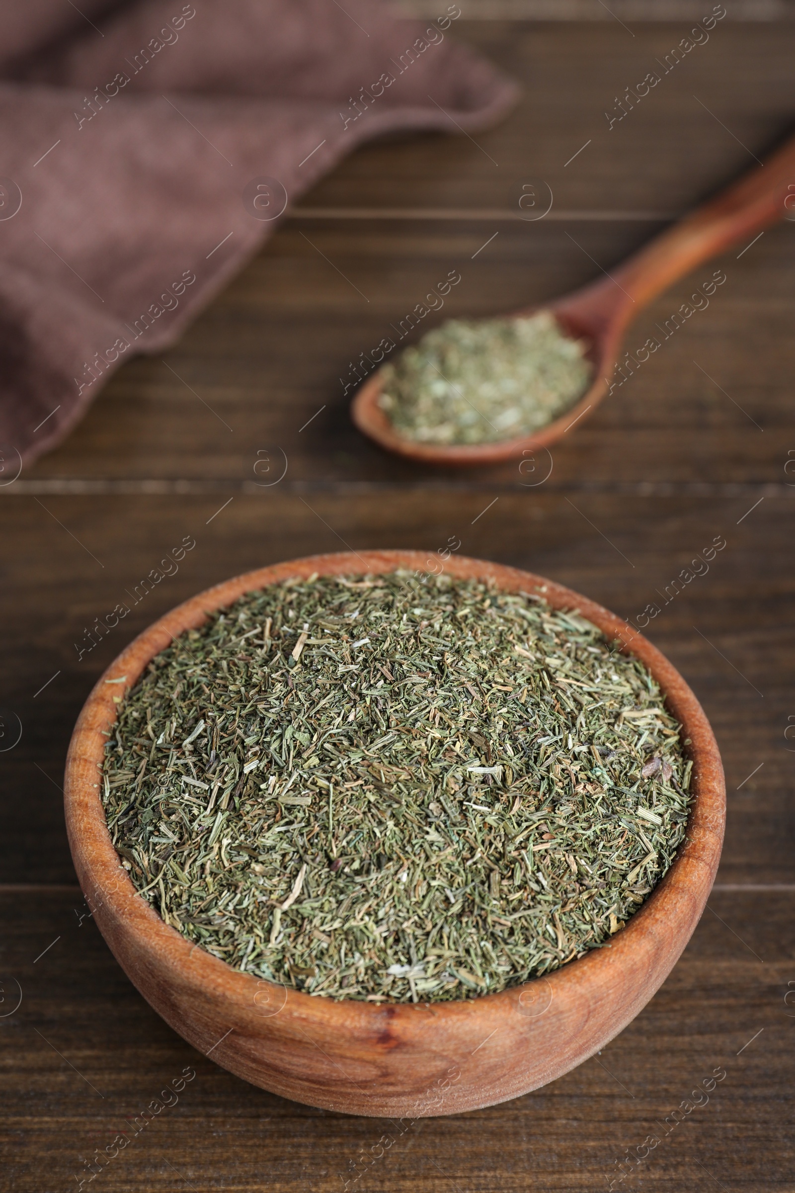 Photo of Bowl and spoon of dried dill on wooden table