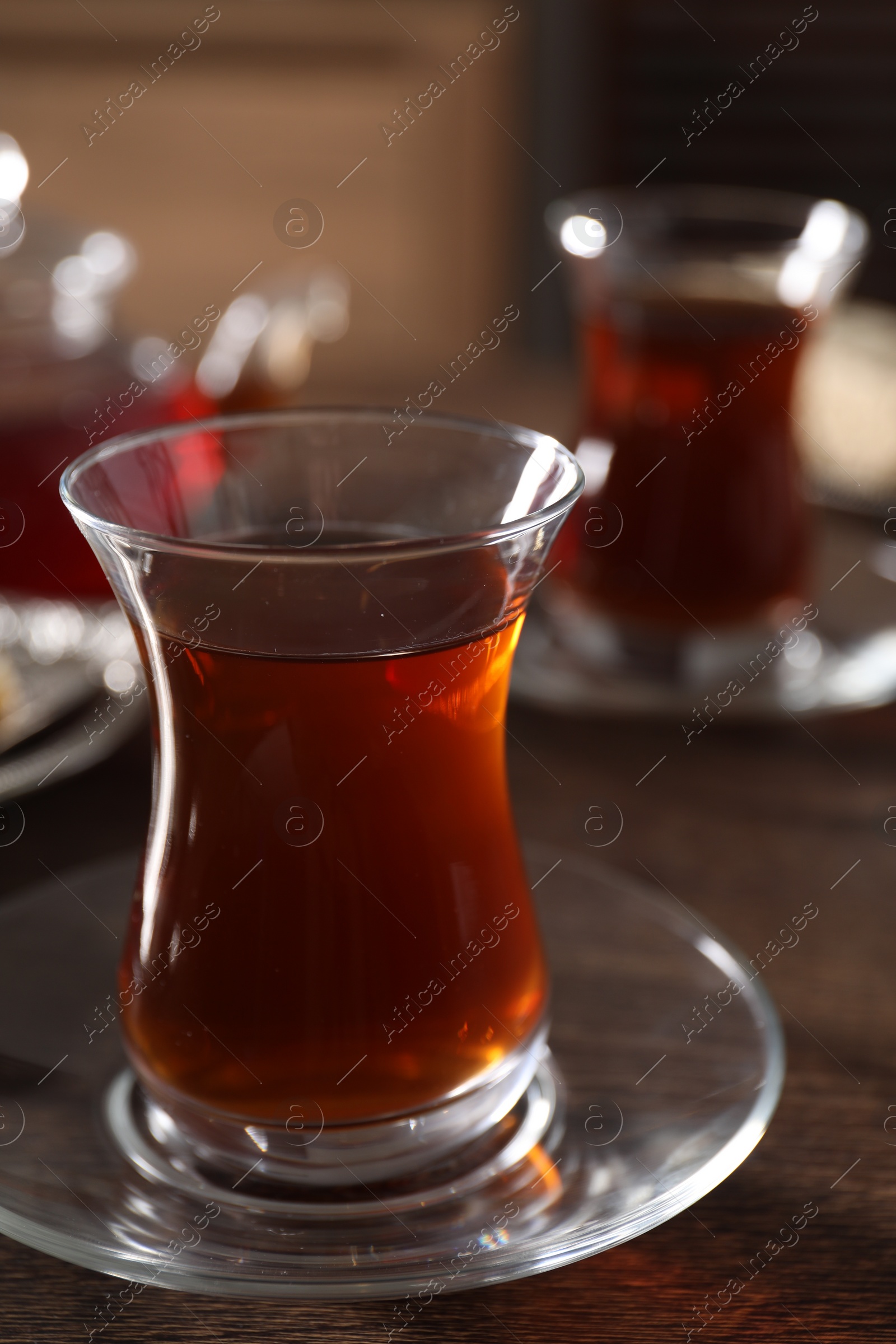 Photo of Traditional Turkish tea in glass on wooden table, closeup