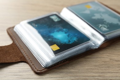 Leather card holder with credit cards on wooden table, closeup