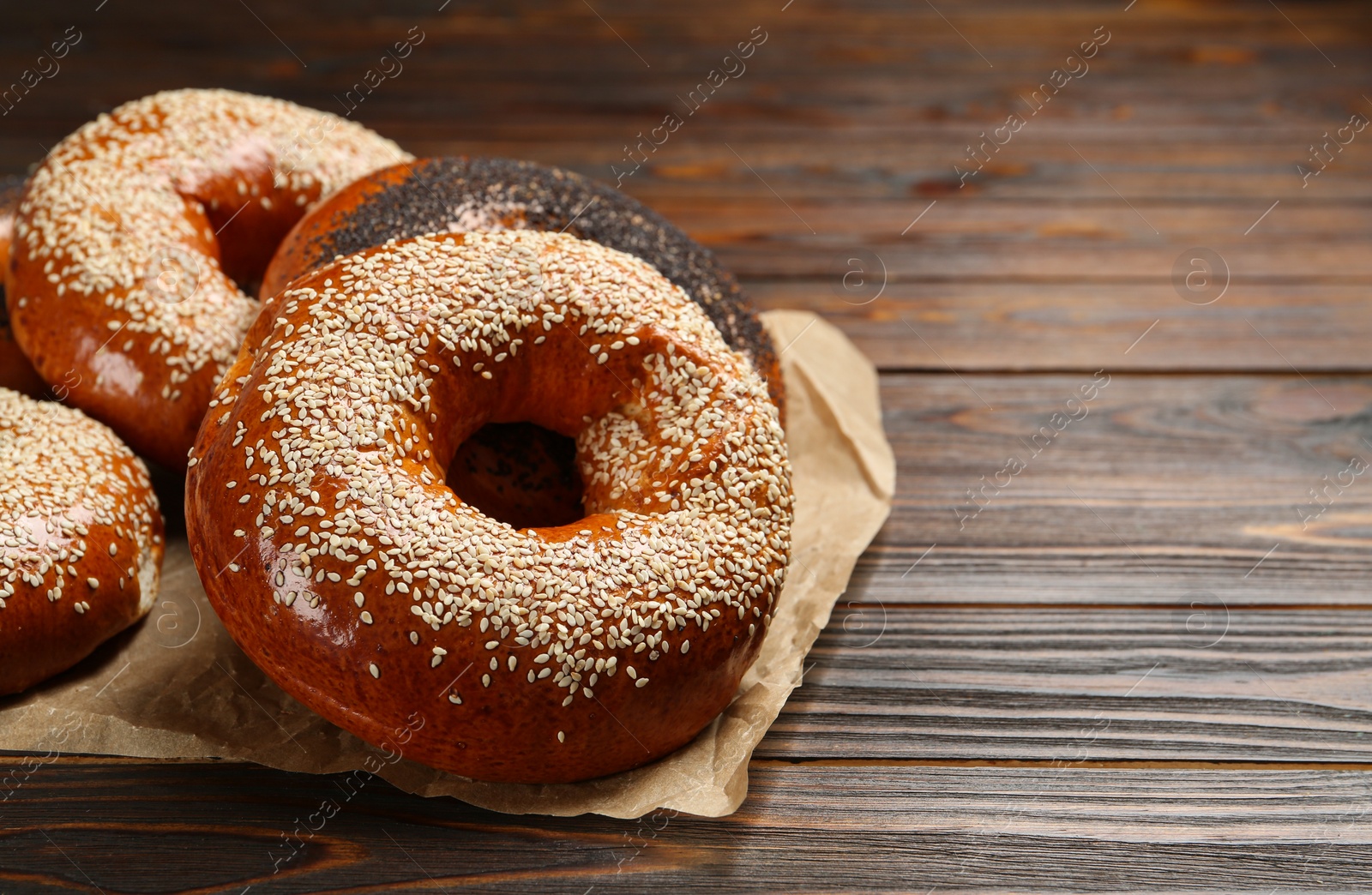 Photo of Many delicious fresh bagels on wooden table, space for text