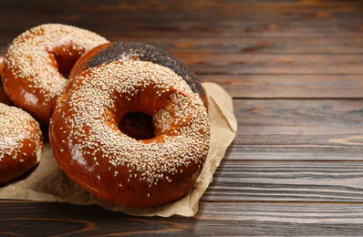 Photo of Many delicious fresh bagels on wooden table, space for text