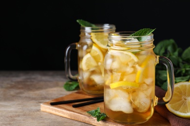 Photo of Delicious iced tea on wooden table against black background, space for text