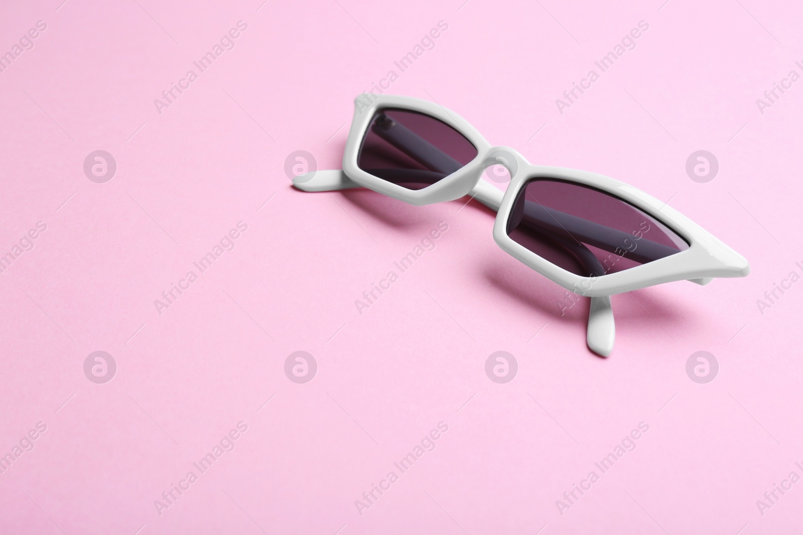 Photo of Stylish sunglasses on pink background, space for text. Fashionable accessory