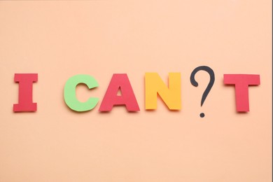 Phrase I Can`t with question mark and letters made of paper on beige background, top view. Motivation concept
