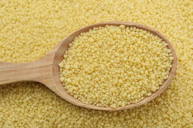 Photo of Spoon with raw couscous as background, top view