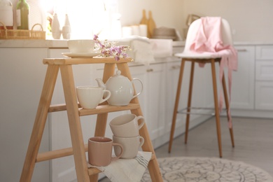 Photo of Decorative ladder with different dishware in kitchen. Idea for interior design