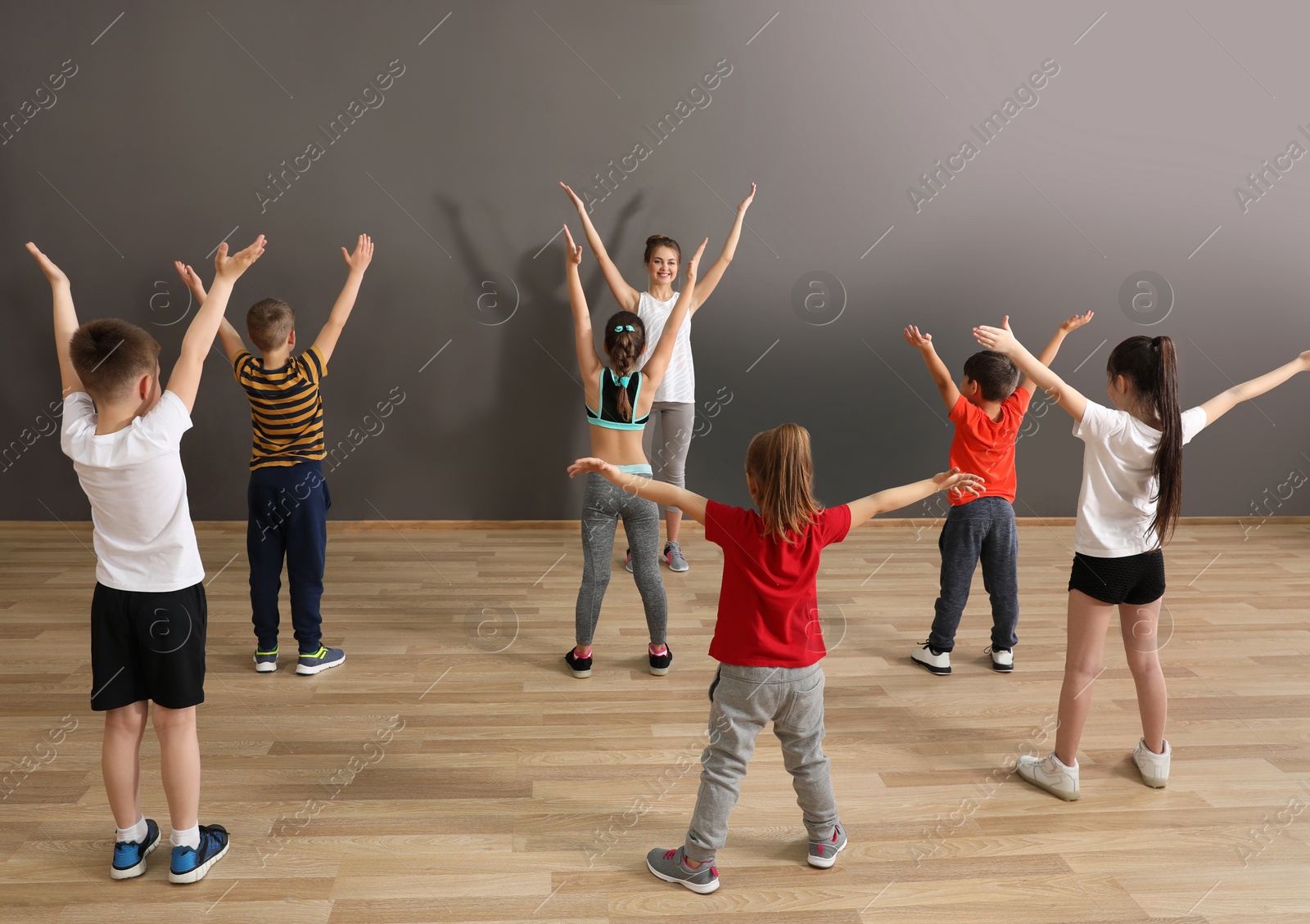 Photo of Cute little children and trainer doing physical exercise in school gym. Healthy lifestyle