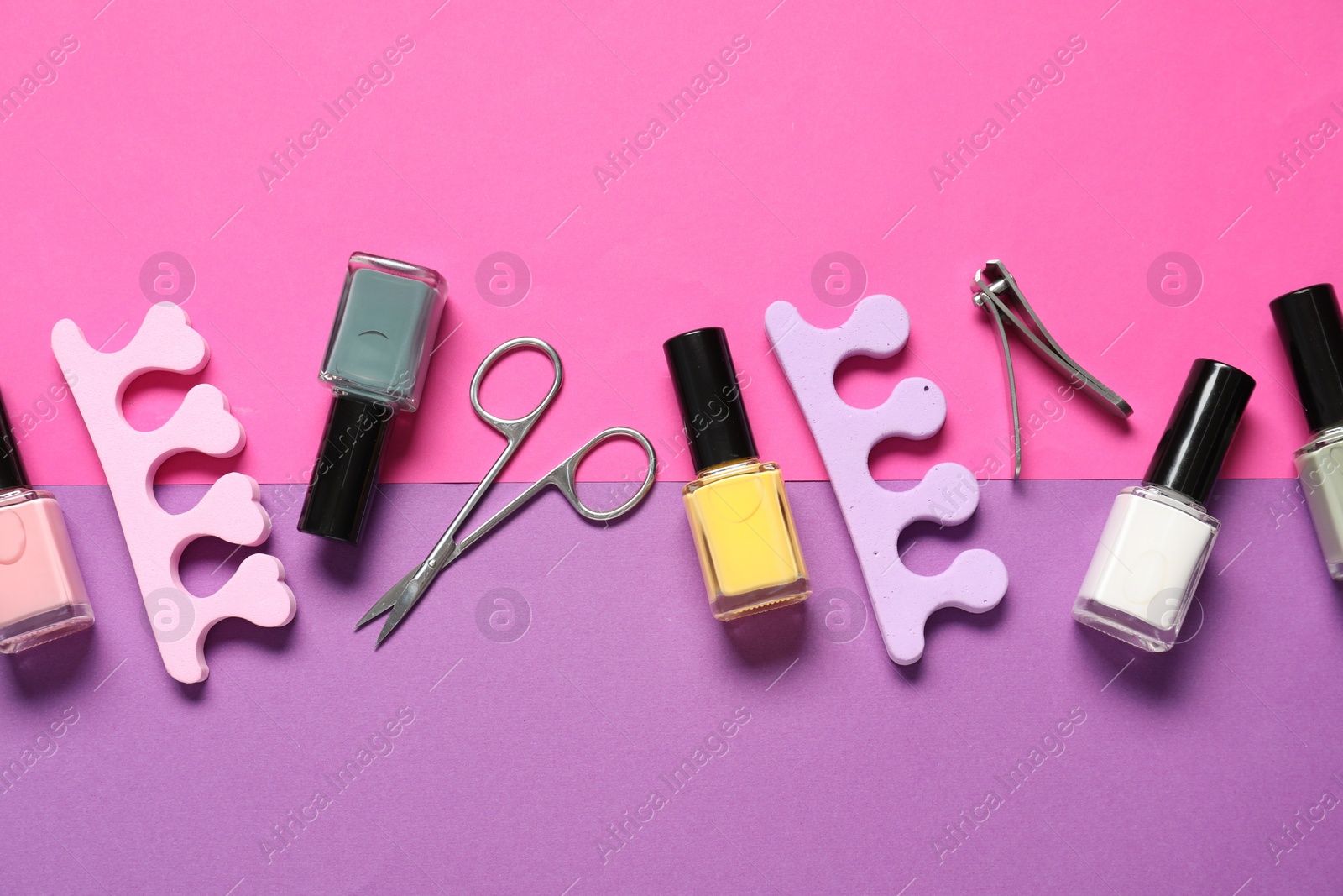 Photo of Nail polishes, clippers, scissors and toe separators on color background, flat lay