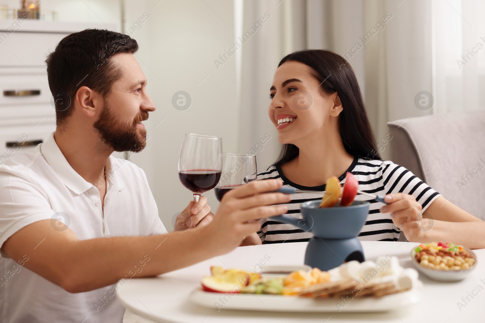 Photo of Affectionate couple enjoying chocolate fondue during romantic date at home