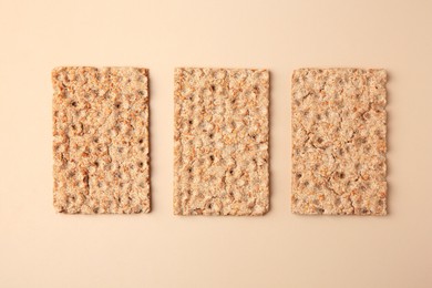 Photo of Fresh crunchy crispbreads on beige background, flat lay